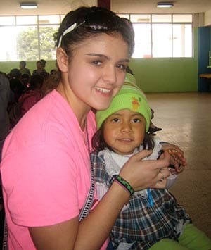 Chiana Román, 16, a sophomore at Divine Savior Holy Angels High School, Milwaukee, holds 3-year-old Catherine Sevilla, on her lap during an all-school Mass on Friday, Jan. 18 at Center One of the Working Boys' Center in Quito, Ecuador. (Catholic Herald photo by Maryangela Layman Roman)