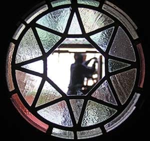 A worker from Louis Hoffmann Company of Menomonee Falls, seen through a glass window, installs a bronze door at Holy Hill on Friday, May 17. (Catholic Herald photos by Steve Wideman)