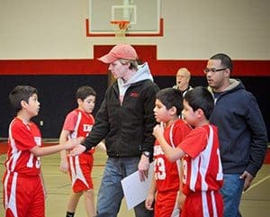 Coach John Meuler congratulates his 2011-2012 fifth grade basketball team after a hard fought game in February 2012. Walking behind him is alumnus McGuiver Lopez-Rodriguez who served as the team’s assistant coach. (Catholic Herald photo by Juan C. Medina)